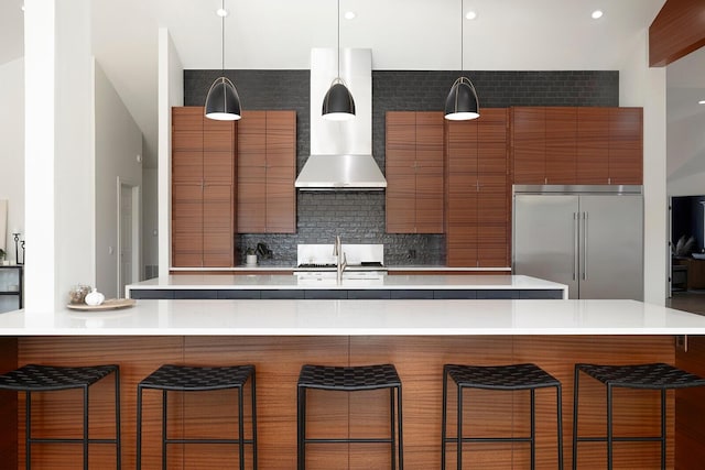 621 S Woodhaven Rd, Nixa, MO 65714 - kitchen with stainless steel built in refrigerator, wall chimney range hood, brown cabinetry, and modern cabinets