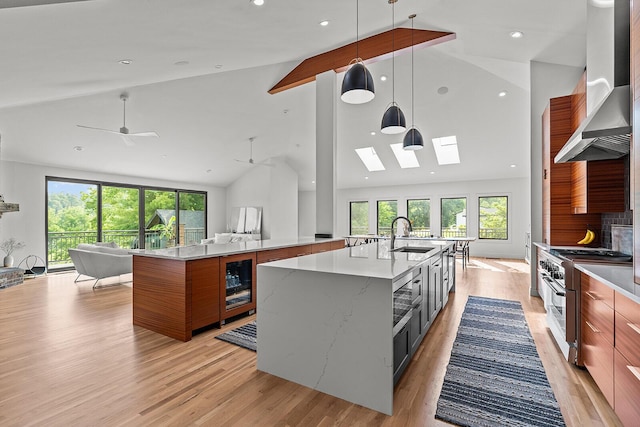 621 S Woodhaven Rd, Nixa, MO 65714 - kitchen featuring wall chimney exhaust hood, open floor plan, high end stainless steel range, a spacious island, and brown cabinets