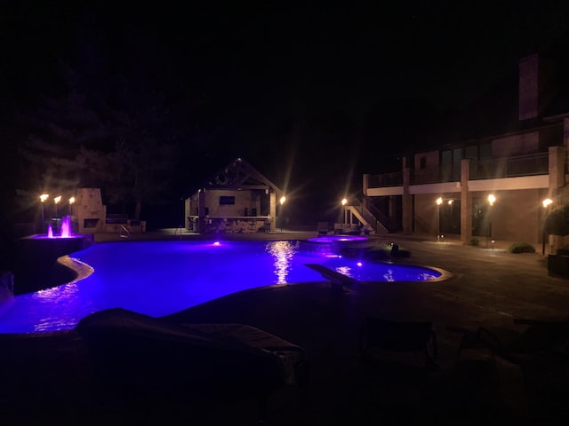 621 S Woodhaven Rd, Nixa, MO 65714 - pool at night featuring an in-ground hot tub, a patio area, and a water slide