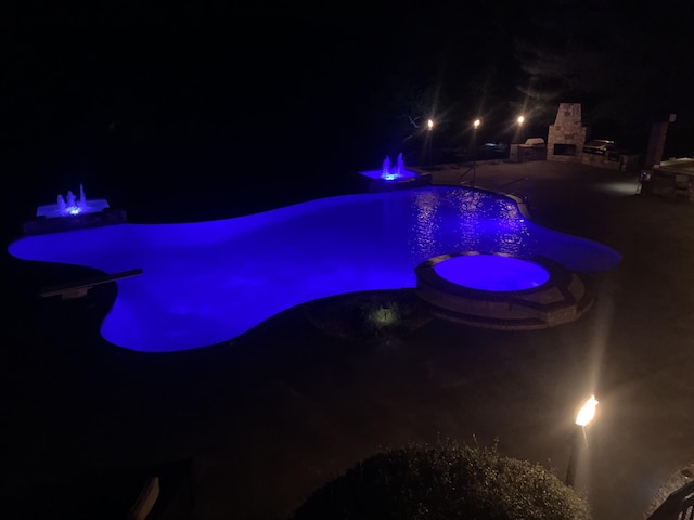 621 S Woodhaven Rd, Nixa, MO 65714 - pool at night featuring a patio area, a pool with connected hot tub, a fire pit, and a fireplace
