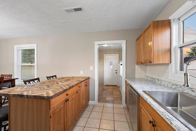 621 S Woodhaven Rd, Nixa, MO 65714 - kitchen with dishwasher, a kitchen bar, a textured ceiling, brown cabinetry, and light tile patterned floors