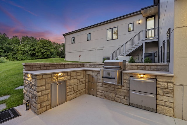 5817 E Summit View Dr, Springfield, MO 65809 - patio terrace at dusk featuring an outdoor kitchen, a patio area, a yard, and stairway