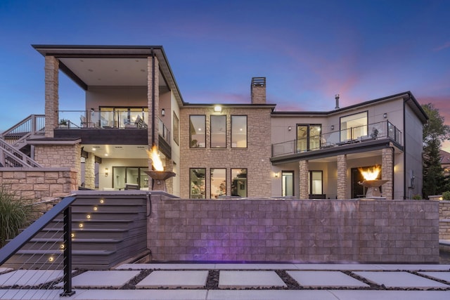 5817 E Summit View Dr, Springfield, MO 65809 - back of house at dusk with a balcony, stairs, and a chimney