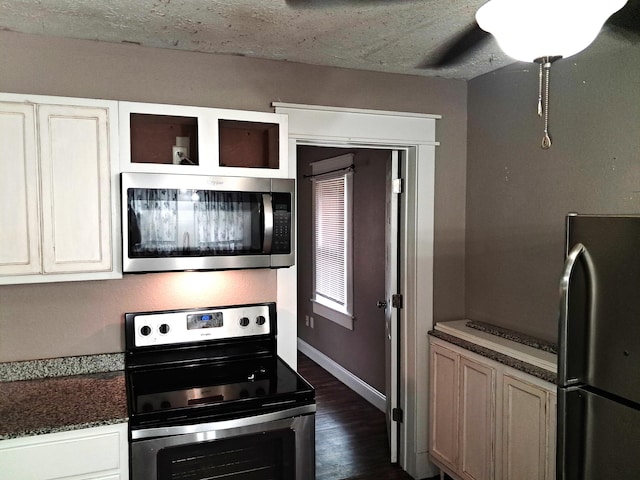 2412 W Olive St, Springfield, MO 65802 - kitchen featuring stainless steel appliances, dark wood-style floors, dark countertops, and a textured ceiling