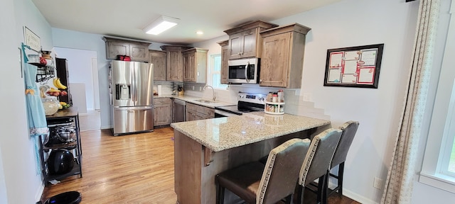 524 Niangua Rd, Niangua, MO 65713 - kitchen with appliances with stainless steel finishes, light wood-style floors, a peninsula, and decorative backsplash