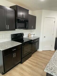 608 N Cheyenne Valley Rd, Nixa, MO 65714 - kitchen with black appliances, light wood-style floors, backsplash, light stone countertops, and dark cabinetry