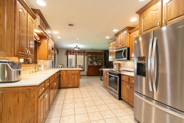 2620 Big Timber Rd, Marshfield, MO 65706 - kitchen with appliances with stainless steel finishes, a peninsula, brown cabinetry, recessed lighting, and light countertops