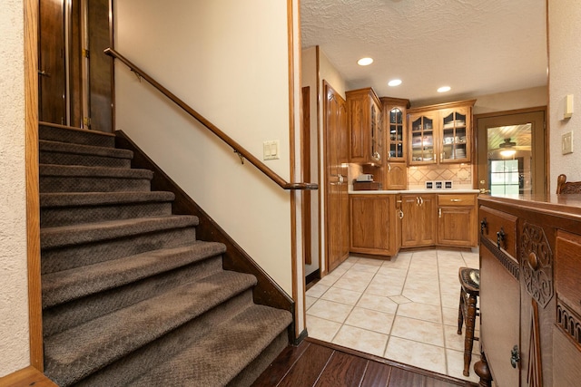 2620 Big Timber Rd, Marshfield, MO 65706 - kitchen featuring brown cabinets, decorative backsplash, glass insert cabinets, recessed lighting, and a textured ceiling