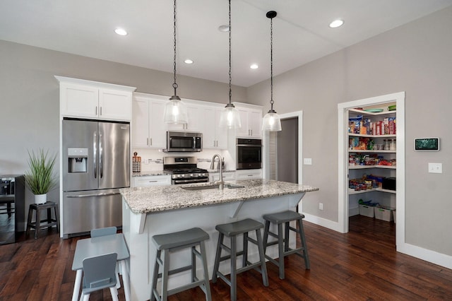 926 E Downshire Dr, Nixa, MO 65714 - kitchen with stainless steel appliances, dark wood-style flooring, white cabinets, a kitchen island with sink, and a kitchen bar