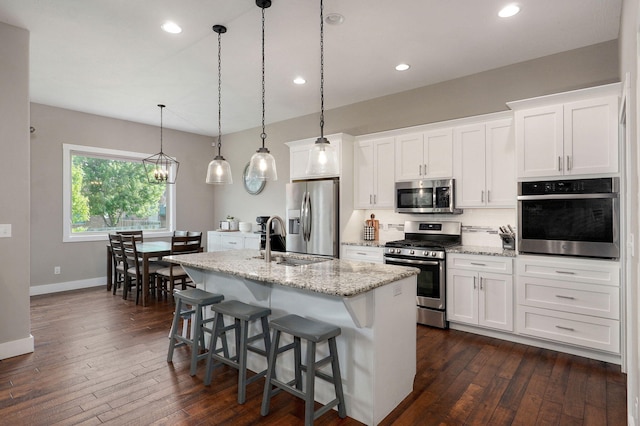 926 E Downshire Dr, Nixa, MO 65714 - kitchen with appliances with stainless steel finishes, a kitchen island with sink, decorative backsplash, dark wood-style floors, and white cabinets