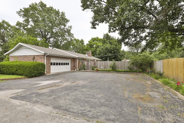 610 W Summit St, Bolivar, MO 65613 - view of home's exterior with asphalt driveway, a garage, a chimney, and brick siding