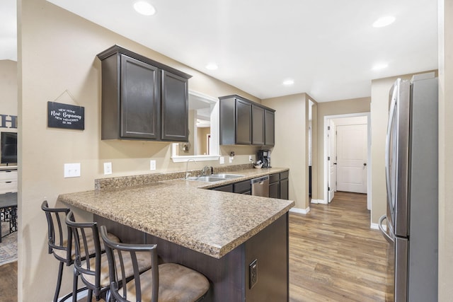 241 Everett Ml Rd, Branson, MO 65616 - kitchen with stainless steel appliances, light wood-style floors, a breakfast bar area, recessed lighting, and a peninsula
