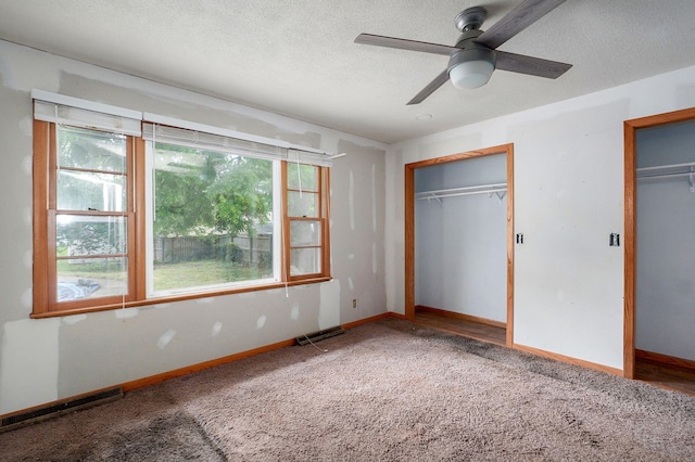 1415 S Sieger Dr, Springfield, MO 65804 - unfurnished bedroom featuring carpet flooring, multiple windows, two closets, a textured ceiling, and ceiling fan
