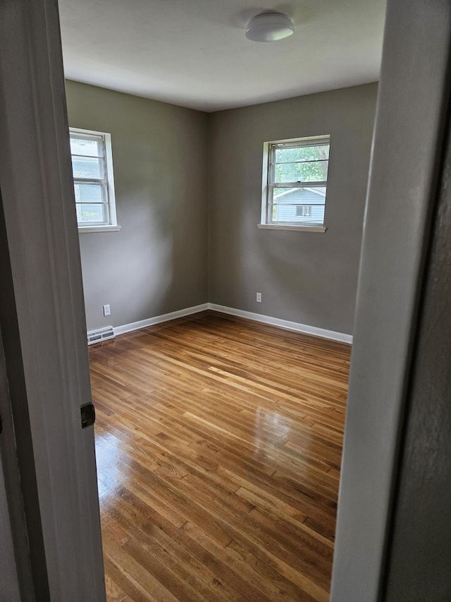 1955 S Fort Ave, Springfield, MO 65807 - empty room featuring plenty of natural light, wood finished floors, and a baseboard heating unit