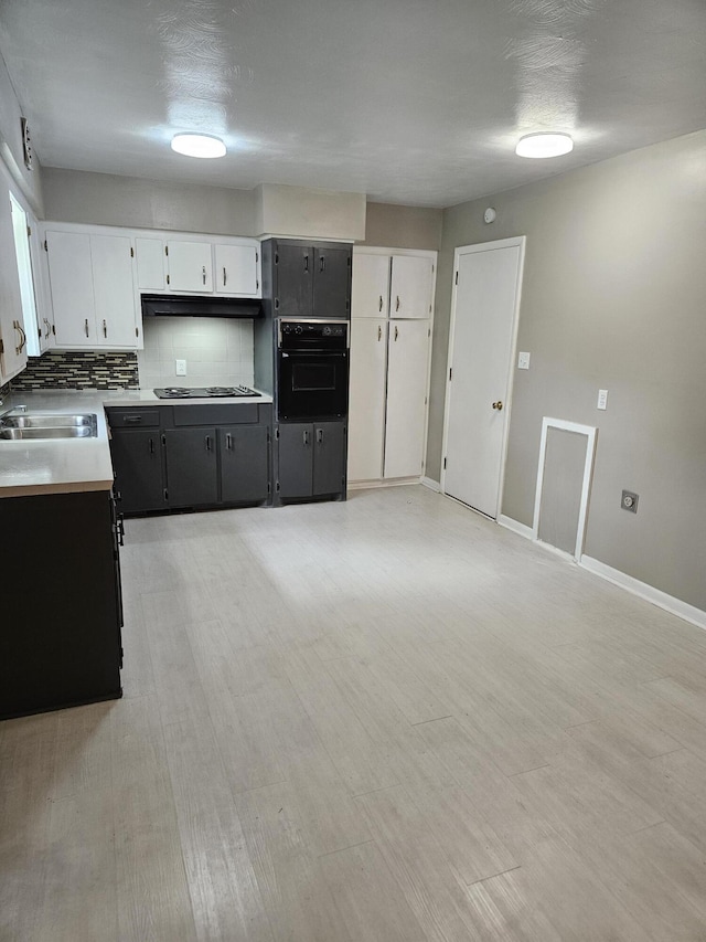 1955 S Fort Ave, Springfield, MO 65807 - kitchen featuring oven, backsplash, cooktop, light countertops, and white cabinetry