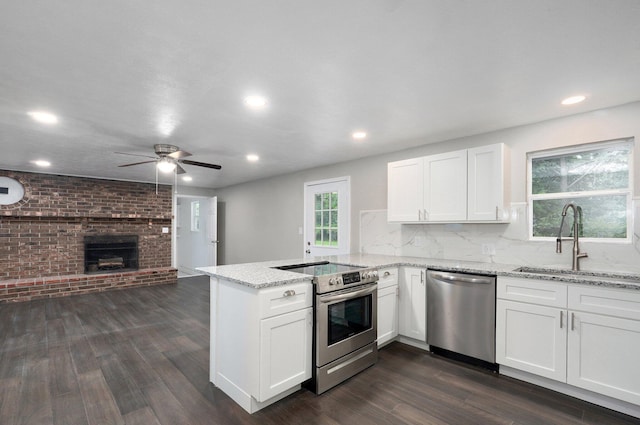 4852 S Fremont Ave, Springfield, MO 65804 - kitchen featuring stainless steel appliances, a peninsula, open floor plan, a brick fireplace, and a ceiling fan