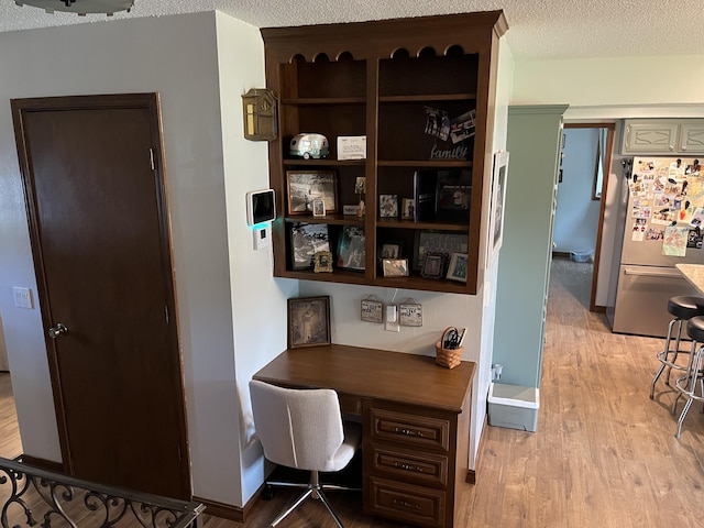 508 E Kirkwood Dr, Aurora, MO 65605 - home office with light wood-style floors, built in desk, and a textured ceiling