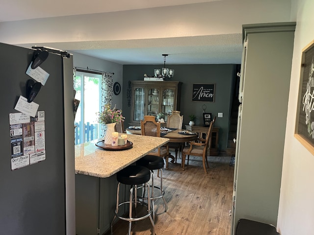 508 E Kirkwood Dr, Aurora, MO 65605 - kitchen featuring freestanding refrigerator, light wood-style floors, a kitchen bar, a chandelier, and pendant lighting