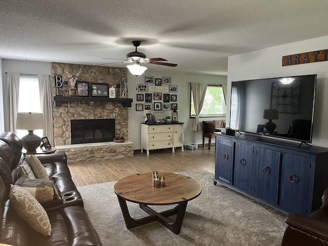 508 E Kirkwood Dr, Aurora, MO 65605 - living room with wood finished floors, plenty of natural light, a stone fireplace, ceiling fan, and a textured ceiling