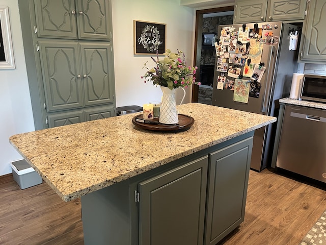 508 E Kirkwood Dr, Aurora, MO 65605 - kitchen with appliances with stainless steel finishes, a center island, light wood finished floors, light stone countertops, and gray cabinets