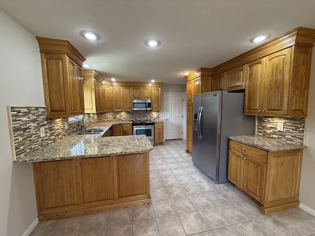 5218 S Gary Ct, Springfield, MO 65810 - kitchen with appliances with stainless steel finishes, a peninsula, light stone counters, decorative backsplash, and brown cabinetry