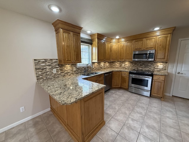 5218 S Gary Ct, Springfield, MO 65810 - kitchen with appliances with stainless steel finishes, a peninsula, backsplash, light stone countertops, and brown cabinetry