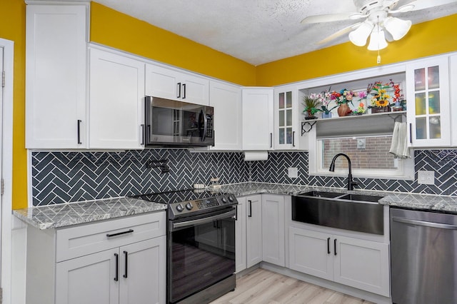 3449 N Rogers Ave, Springfield, MO 65803 - kitchen featuring appliances with stainless steel finishes, light wood-type flooring, white cabinetry, ceiling fan, and glass insert cabinets