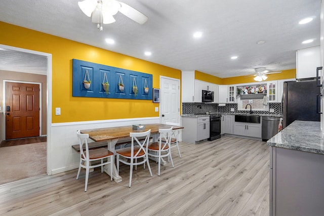 3449 N Rogers Ave, Springfield, MO 65803 - kitchen featuring ceiling fan, black appliances, light wood-style flooring, glass insert cabinets, and wainscoting