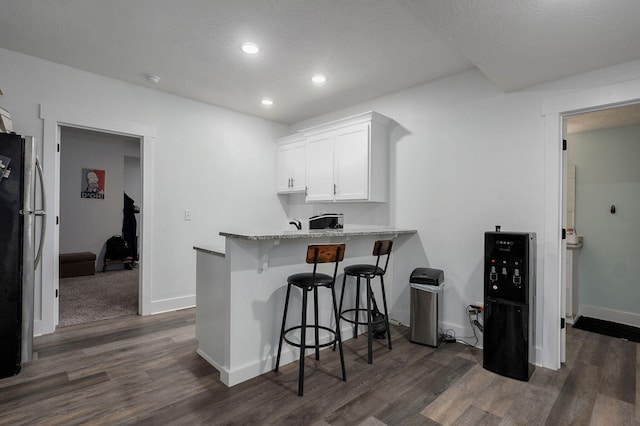 1611 E Hayloft Dr, Ozark, MO 65721 - kitchen with a breakfast bar area, white cabinets, dark wood-style flooring, freestanding refrigerator, and recessed lighting