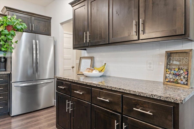 1651 N Penrose Ave, Nixa, MO 65714 - kitchen featuring freestanding refrigerator, dark brown cabinets, decorative backsplash, wood finished floors, and light stone countertops