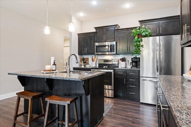 1651 N Penrose Ave, Nixa, MO 65714 - kitchen with stainless steel appliances, a kitchen bar, dark wood-type flooring, dark stone counters, and recessed lighting