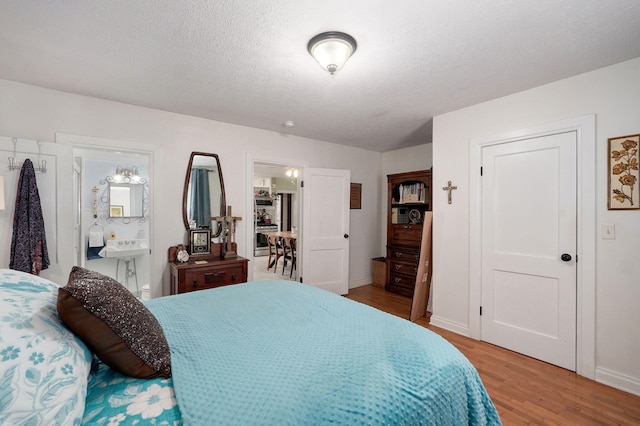 223 E Mill St, Republic, MO 65738 - bedroom featuring light wood-style flooring, ensuite bath, and a textured ceiling