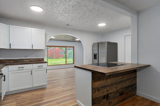 1317 S Willow Ave, Springfield, MO 65804 - kitchen featuring wood counters, black electric stovetop, arched walkways, white cabinets, and light wood-style flooring