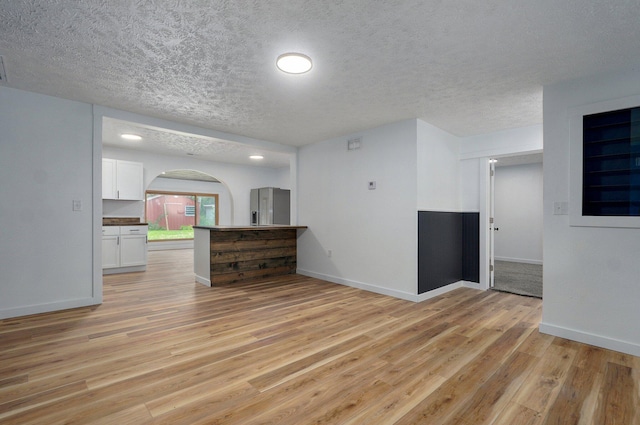 1317 S Willow Ave, Springfield, MO 65804 - unfurnished living room with light wood-style floors, arched walkways, and a textured ceiling