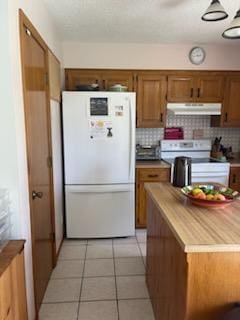 177 Marla Cir, Ozark, MO 65721 - kitchen featuring freestanding refrigerator, stove, under cabinet range hood, brown cabinetry, and light tile patterned floors