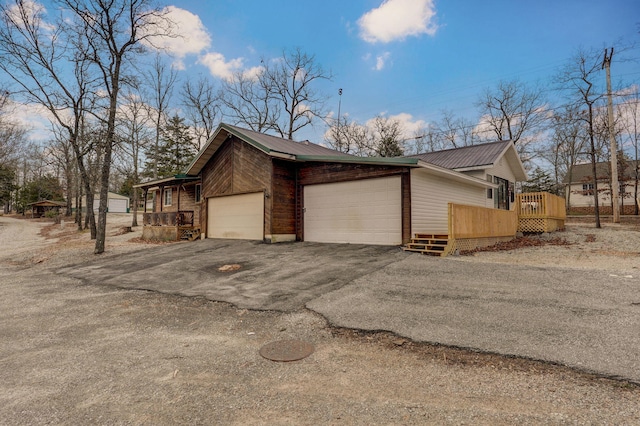 131 Forest Ln, Kimberling City, MO 65686 - view of side of property with asphalt driveway, a garage, a deck, and a metal roof