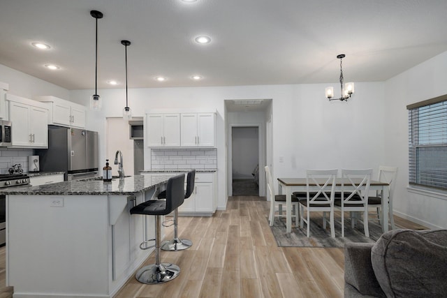 842 E Acacia Ln, Nixa, MO 65714 - kitchen with appliances with stainless steel finishes, a breakfast bar, tasteful backsplash, dark stone counters, and recessed lighting