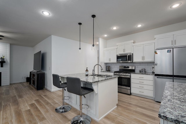 842 E Acacia Ln, Nixa, MO 65714 - kitchen featuring appliances with stainless steel finishes, light wood-style floors, a breakfast bar area, decorative backsplash, and light stone counters