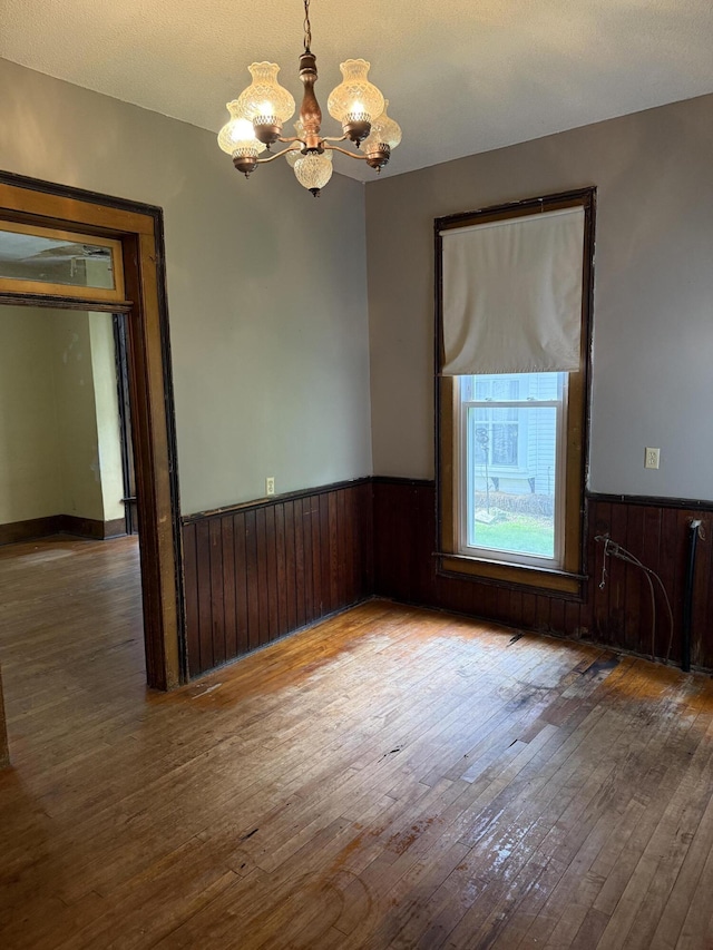 405 N Walnut St, Pierce City, MO 65723 - spare room featuring a chandelier, hardwood / wood-style flooring, wainscoting, and wood walls