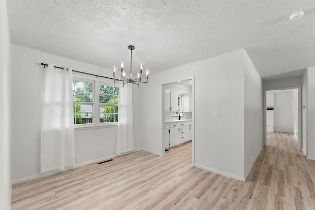 2443 S Kickapoo Ave, Springfield, MO 65804 - unfurnished dining area with light wood-style floors, a chandelier, and a textured ceiling