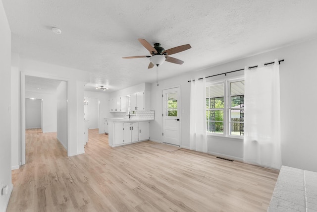 2443 S Kickapoo Ave, Springfield, MO 65804 - unfurnished living room with a ceiling fan, light wood-style flooring, and a textured ceiling