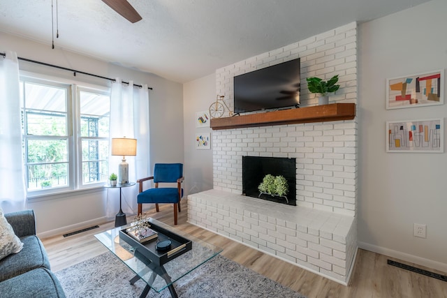 2443 S Kickapoo Ave, Springfield, MO 65804 - living room with wood finished floors, healthy amount of natural light, a brick fireplace, ceiling fan, and a textured ceiling