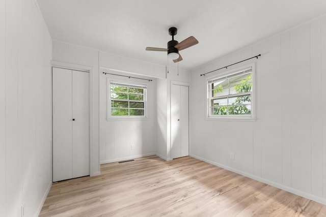 2443 S Kickapoo Ave, Springfield, MO 65804 - unfurnished bedroom featuring two closets, multiple windows, light wood-style floors, and a ceiling fan