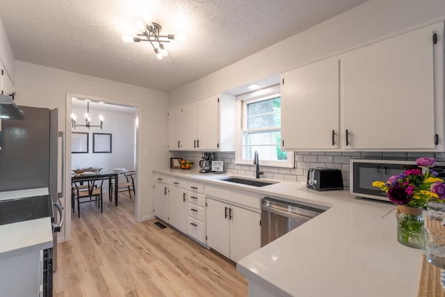2443 S Kickapoo Ave, Springfield, MO 65804 - kitchen featuring a textured ceiling, stainless steel appliances, light countertops, white cabinetry, and backsplash