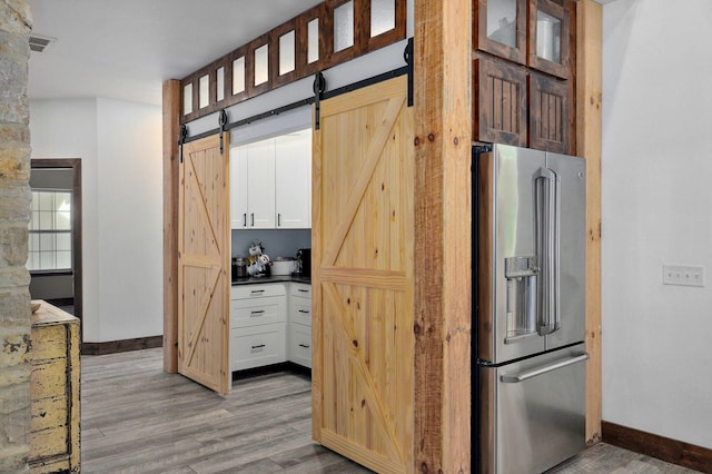 1721 Jackson Spring Rd, Ozark, MO 65721 - kitchen with high quality fridge, a barn door, light wood-type flooring, dark countertops, and glass insert cabinets