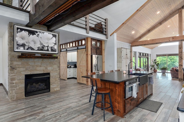 1721 Jackson Spring Rd, Ozark, MO 65721 - kitchen with dark countertops, light wood-style flooring, a barn door, high vaulted ceiling, and a wooden ceiling with exposed beams