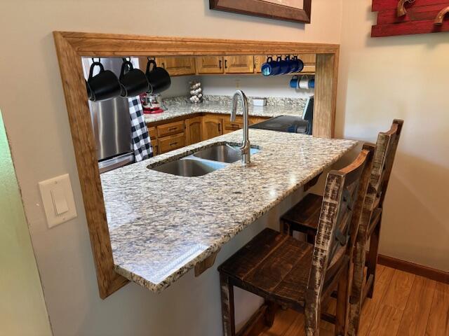 21572 Lawrence Unit 1240, Aurora, MO 65605 - kitchen featuring wood finished floors, a kitchen breakfast bar, and brown cabinets