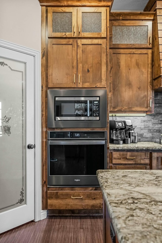 416 W Saddle Club Rd, Fair Grove, MO 65648 - kitchen with appliances with stainless steel finishes, dark wood-style flooring, light stone counters, glass insert cabinets, and brown cabinets