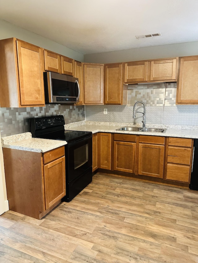 652 W Hovey St, Springfield, MO 65802 - kitchen with stainless steel microwave, black range with electric cooktop, decorative backsplash, and light wood-style floors