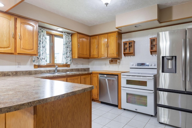 3047 S Ferguson Ave, Springfield, MO 65807 - kitchen featuring stainless steel appliances, light tile patterned floors, a textured ceiling, brown cabinets, and decorative backsplash